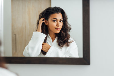 Smiling young woman looking in mirror