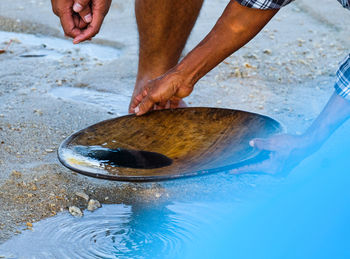 Midsection of man holding fish at beach