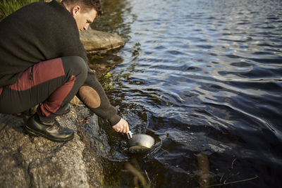 Man washing dishes in lake