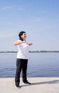 Full length of young man standing in lake against sky