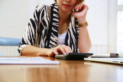 Midsection of man using mobile phone on table
