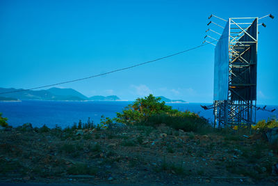 Electricity pylon on land against blue sky