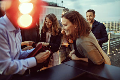 Business people discussing over gifts during office party on terrace