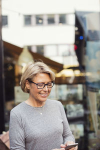 Happy businesswoman using smart phone at sidewalk cafe