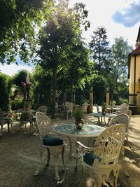 Empty chairs and table in park against sky