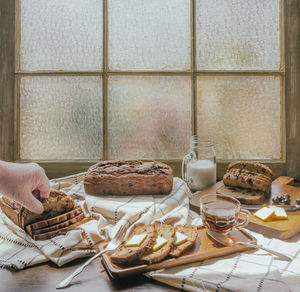 High-angle view of human hand reaching for banana bread