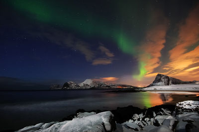 Scenic view of sea and mountains against sky at night