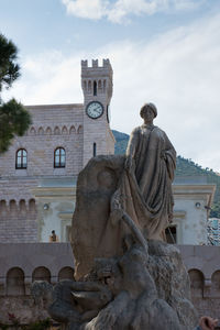 Low angle view of statue against building against sky