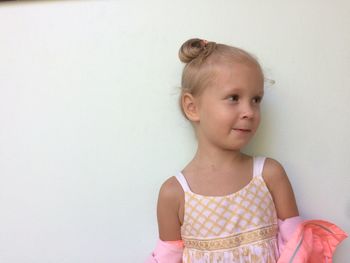 Close-up of girl standing against white wall