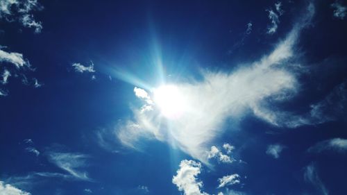 Low angle view of sunlight streaming through clouds