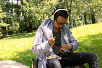 Casual man adjusting headphones while spending spring day in nature.