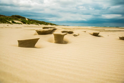 Sand dune on beach against sky