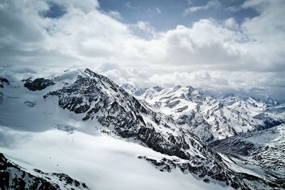 Scenic view of snowcapped mountains against cloudy sky