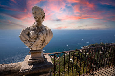 Statue by sea against sky during sunset