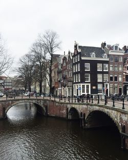 Bridge over river in city against sky