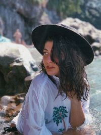 Woman wearing hat sitting at beach