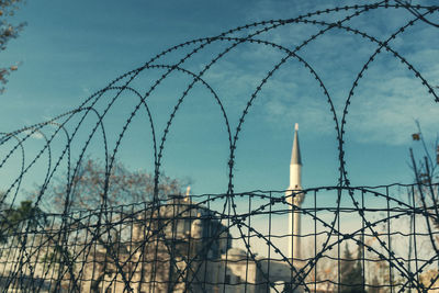 Low angle view of barbed wire fence against sky