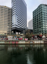 Bridge over river by buildings against sky in city