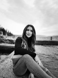 Portrait of beautiful young woman sitting on land