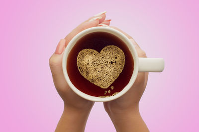 Midsection of man holding coffee cup against pink background