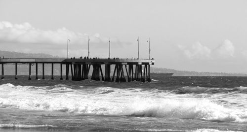Wooden posts in sea against sky