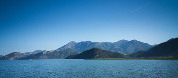 Panoramic shot of lake by mountains against blue sky