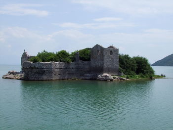 Abandoned prison amidst lake skadar against sky