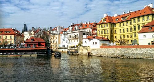 Buildings by river against sky in city