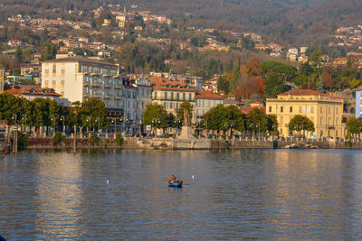 People by lake against buildings in city