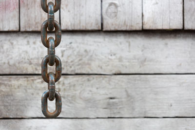 Broad metal anchor chain against wood panel 