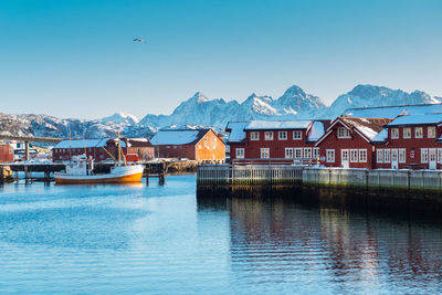 Houses by lake and buildings against clear sky
