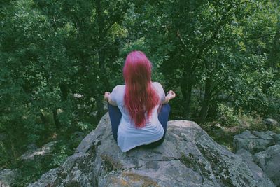 Rear view of woman sitting on tree