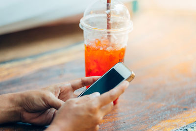 Midsection of person holding ice cream cone on table