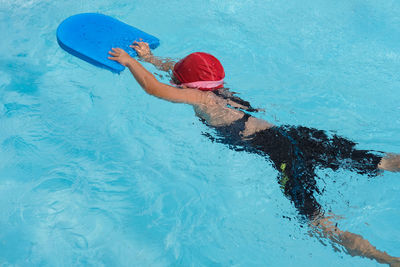 High angle view of girl holding equipment while sitting in pool