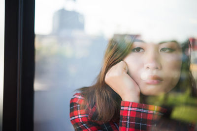 Sad woman looking away seen through window