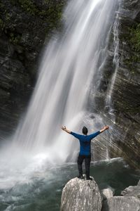 Man standing on rock against waterfall