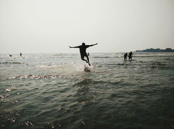 Silhouette man jumping on sea against sky