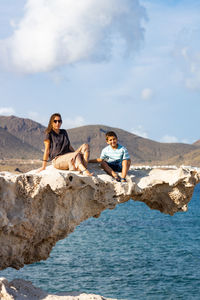 Woman and kid on a rock of playa del arco, almeria, spain