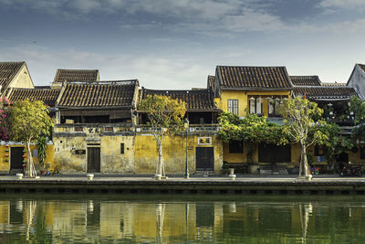 Buildings by lake against sky in city