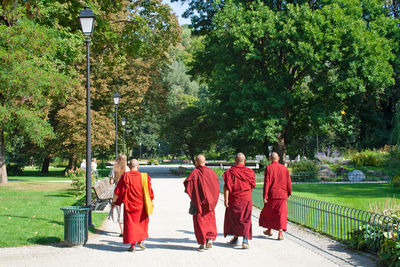 Rear view of monks wearing traditional clothing while walking on footpath in park