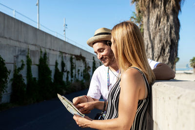 Happy tourist couple checking a city map outdoors in a sunny day