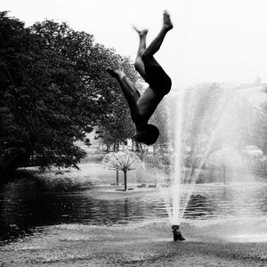 People in water fountain against trees