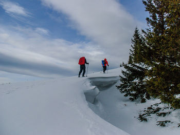 People on snow covered landscape against sky