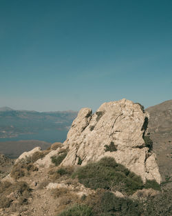 Rock formations on landscape against clear blue sky