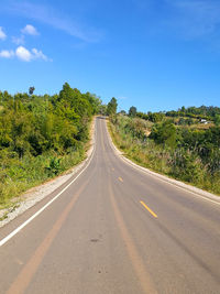 Road amidst trees against clear blue sky