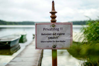 Close-up of information sign against sky