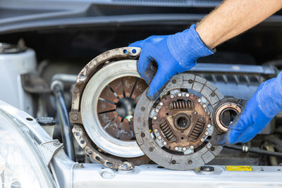 Car technician holding used clutch set assembly - friction, pressure plate and release bearing