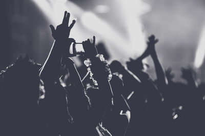 Silhouette people with arms outstretched standing at music concert