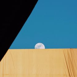 Low angle view of moon against clear blue sky