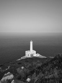 Lighthouse by sea against sky